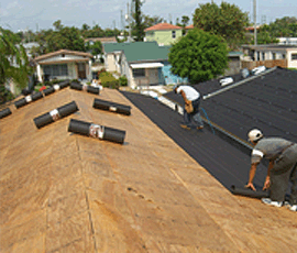 Men rolling new underlayment on a roof.