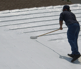 White painted roof by man with a long handed roller.
